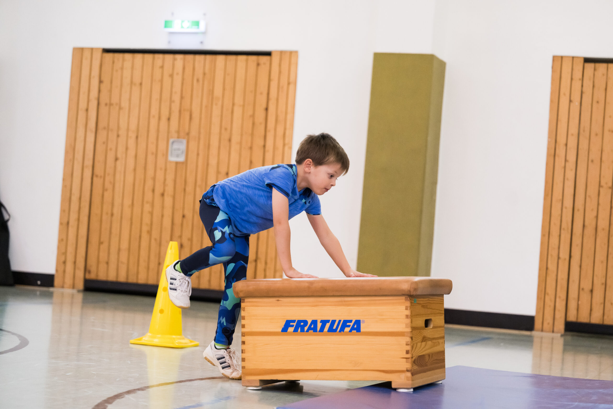 Ein Kind in der Turnhalle klettert auf einen kleinen Kasten.